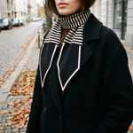 Elodie skinny knit scarf worn with a black wool coat in autumn