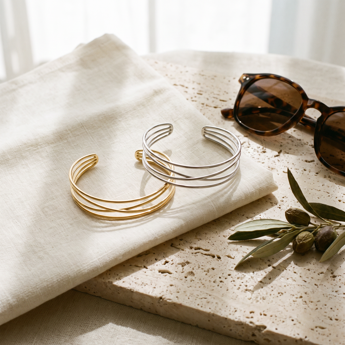 Ilona crossover arm cuffs in gold and silver side by side on linen