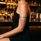 Livia silver draped chain arm cuff worn with a black one-shoulder dress