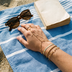 Ondine gold hand chain set worn on a beach towel