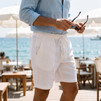 Tobin white linen shorts worn on a seaside cafe terrace