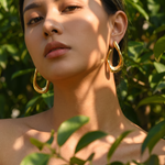 Amara sculpted gold hoop worn in dappled sunlight