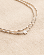 Fleur body chain arranged on cream linen