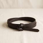 Noor knot belt in coffee brown, coiled on cream linen