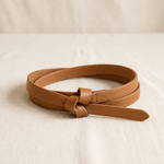Noor knot belt in camel, coiled on cream linen