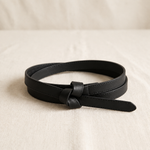 Noor knot belt in black, coiled on cream linen
